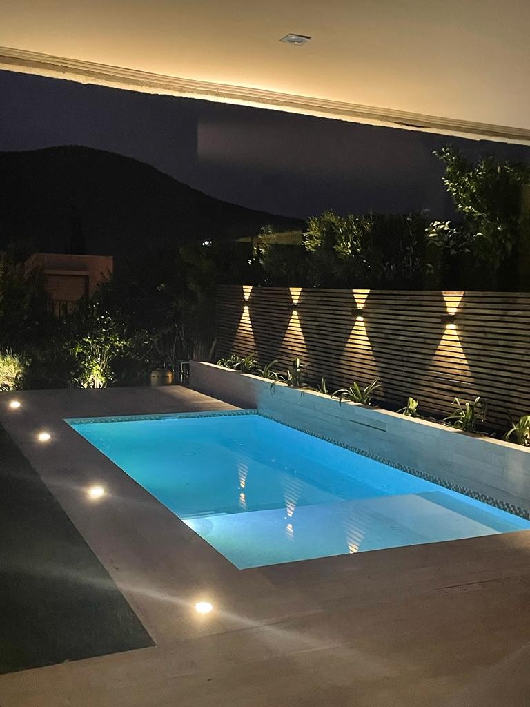 Piscina AcuaNova Chicureo con iluminación LED nocturna y diseño velo con jardineras
